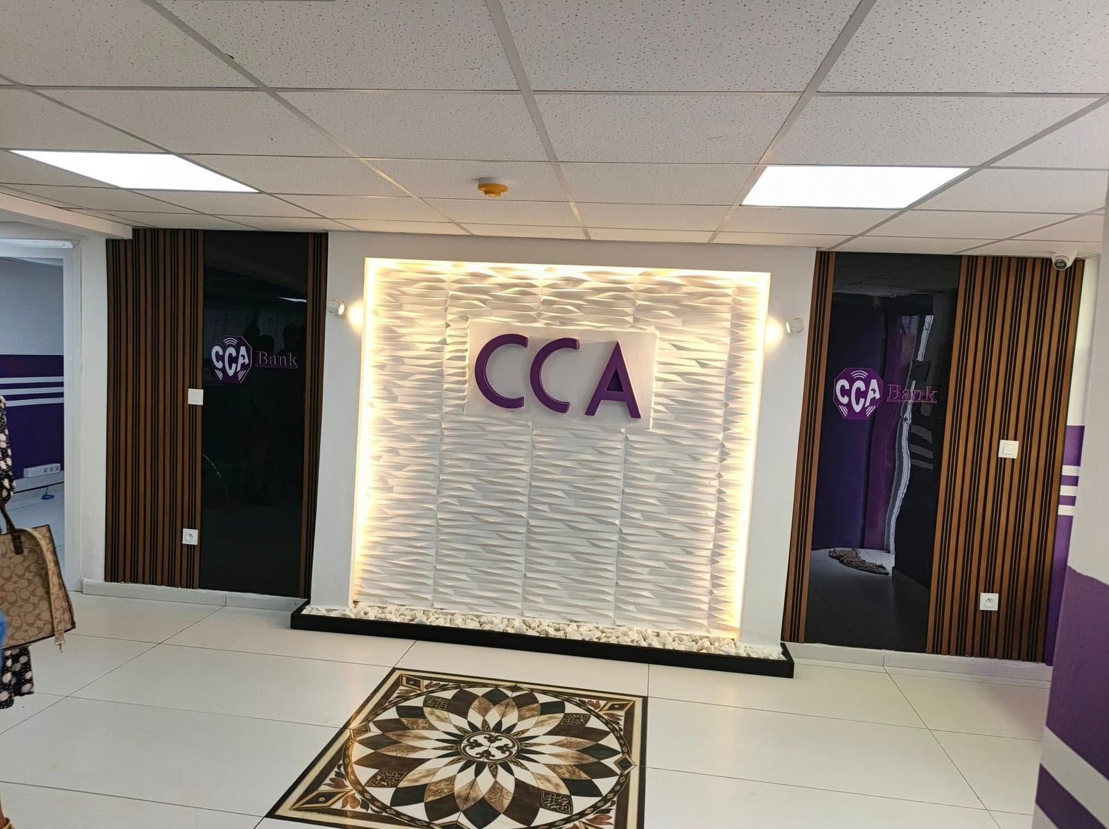 Hall d’accueil : mur texturé rétroéclairé au logo CCA, lames bois et rosace en marbre