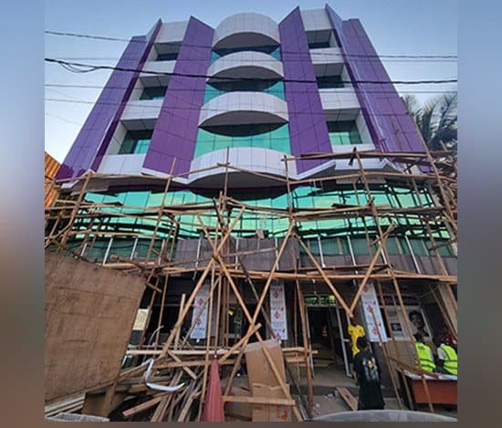 Immeuble de plusieurs niveaux en finition, façade violette sous échafaudage