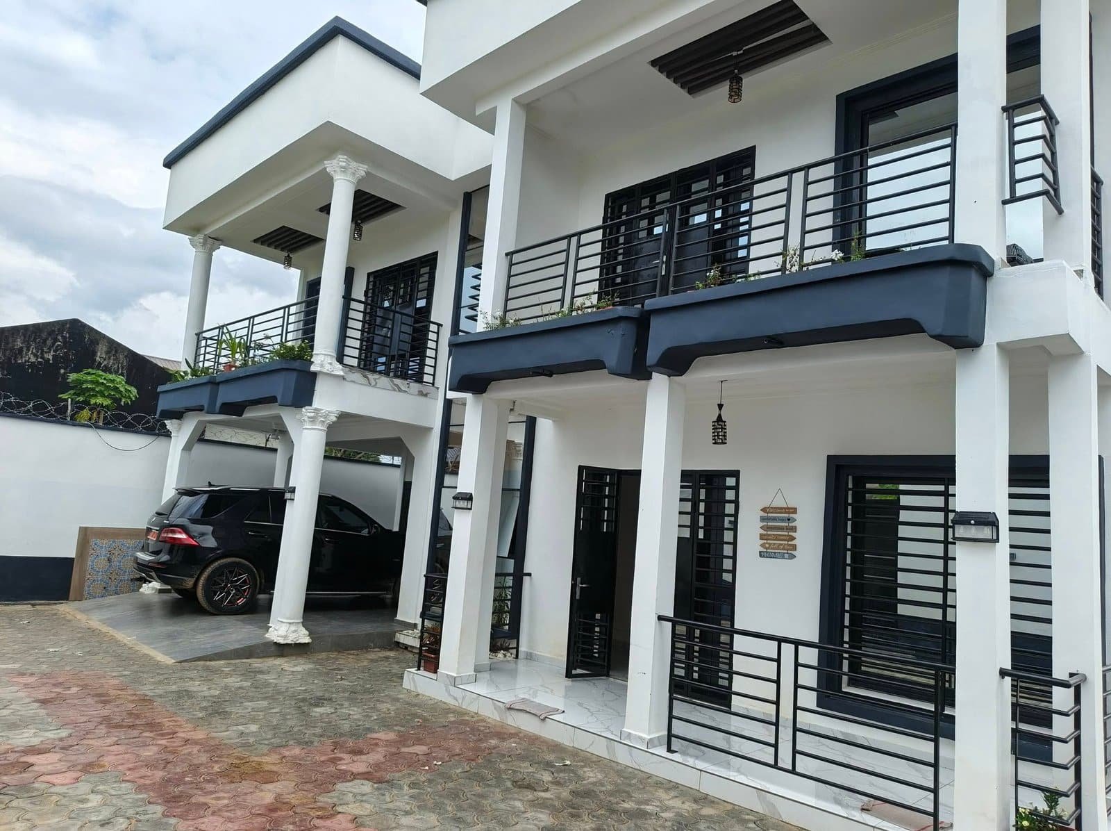 Façade de la villa sur deux niveaux, balcons noirs et colonnes blanches